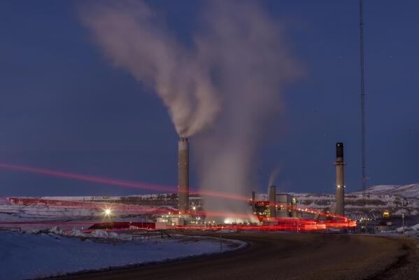 In this photo taken with a slow shutter speed, taillights trace the path of a motor vehicle at the Naughton Power Plant, Thursday, Jan. 13, 2022 in Kemmerer, Wyo. While the power plant will be closed in 2025, Bill Gates' company TerraPower announced it had chosen Kemmerer for a nontraditional, sodium-cooled nuclear reactor that will bring on workers from a local coal-fired power plant scheduled to close soon. (AP Photo/Natalie Behring)