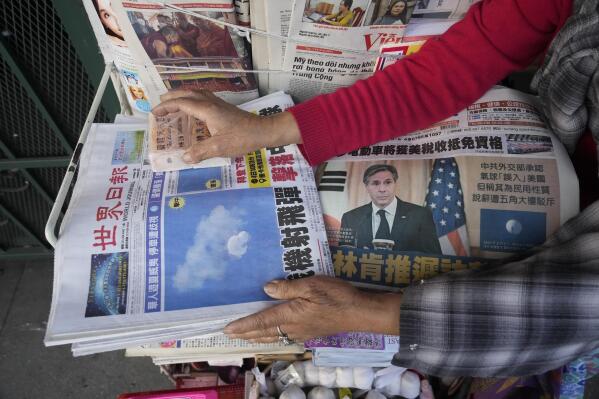 Business owner "Annie" weights down copies of the Chinese Daily News newspaper showcasing pictures of a suspected Chinese spy balloon, in the Chinatown district of Los Angeles Sunday, Feb. 5, 2023. The balloon's presence in the sky above the United States before a military jet shot it down over the Atlantic Ocean with a missile Saturday has further strained U.S.- China ties. (AP Photo/Damian Dovarganes)