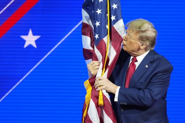 Republican presidential candidate former President Donald Trump hugs and kisses the American flag as he speaks at the Conservative Political Action Conference, CPAC 2024, at National Harbor, in Oxon Hill, Md., Saturday, Feb. 24, 2024. (AP Photo/Alex Brandon)