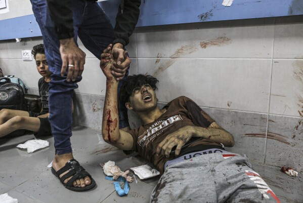 Wounded Palestinians lie on the floor in Shifa Hospital in Gaza City, central Gaza Strip, after arriving from al-Ahli Hospital following an explosion there, Tuesday, Oct. 17, 2023. (AP Photo/Abed Khaled)
