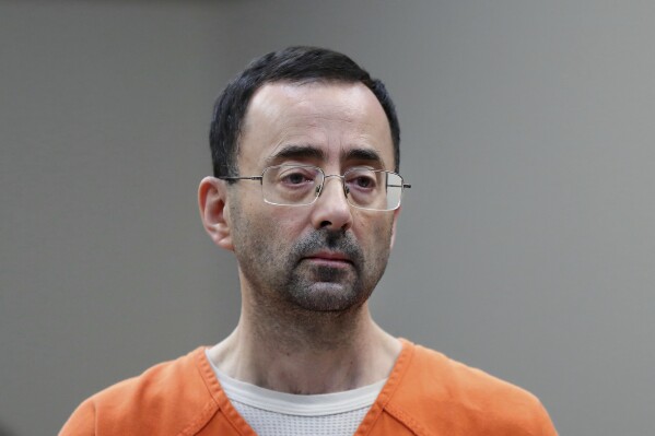 FILE - Disgraced former sports doctor Larry Nassar appears in court for a plea hearing, Nov. 22, 2017, in Lansing, Mich. Women sexually assaulted by imprisoned former Michigan State University sports doctor Larry Nassar have filed a lawsuit, Thursday, July 27, 2023, claiming school officials made “secret decisions” about releasing documents in the case. (AP Photo/Paul Sancya, File)