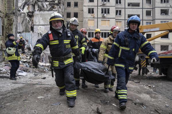 Rescue workers carry the body of a man who was killed in a Russian missile strike on an apartment building in the southeastern city of Dnipro, Ukraine, Monday, Jan. 16, 2023. (AP Photo/Evgeniy Maloletka)