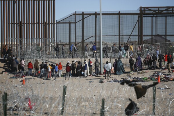 Migrants wait in line after being detained by U.S. immigration authorities at the U.S. border wall, seen from Ciudad Juarez, Mexico, Wednesday, Dec. 27, 2023. (AP Photo/Christian Chavez)