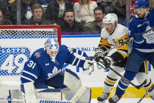 Toronto Maple Leafs defenseman Timothy Liljegren (37) holds off Pittsburgh Penguins' Sidney Crosby (87) as Leafs goaltender Martin Jones (31) makes a save during the second period of an NHL hockey game Saturday, Dec. 16, 2023, in Toronto. (Frank Gunn/The Canadian Press via AP)