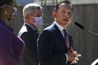 San Francisco City Attorney David Chiu, right, stands next to Mayor London Breed, left, and City Attorney Dennis Herrera as he speaks during a press conference on Wednesday, Sept. 29, 2021 in San Francisco, Calif. Chiu has issued subpoenas seeking records from an unauthorized COVID-19 test operator and laboratory suspected of offering free testing in the city as the fast-spreading omicron variant drove up demand for testing. Chiu said "We cannot allow rogue actors to exploit this omicron surge for profit," (Lea Suzuki/San Francisco Chronicle via AP)