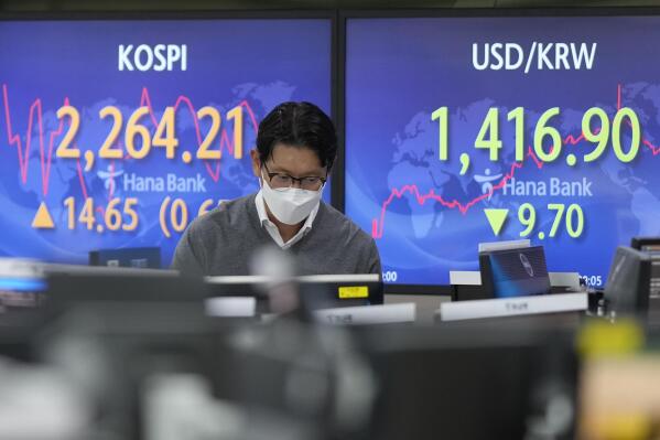 A currency trader walks by the screens showing the Korea Composite Stock Price Index (KOSPI), left, and the foreign exchange rate between U.S. dollar and South Korean won at a foreign exchange dealing room in Seoul, South Korea, Thursday, Oct. 27, 2022. Asian stock markets were mixed Thursday ahead of an update on the U.S. economy and a European Central Bank meeting that is expected to raise its key interest rate to a 13-year high. (AP Photo/Lee Jin-man)