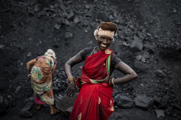 An Indian laborer smiles as she takes a break from loading coal into a truck in Dhanbad, an eastern Indian city in Jharkhand state, Friday, Sept. 24, 2021. A 2021 Indian government study found that Jharkhand state -- among the poorest in India and the state with the nation’s largest coal reserves -- is also the most vulnerable Indian state to climate change. Efforts to fight climate change are being held back in part because coal, the biggest single source of climate-changing gases, provides cheap electricity and supports millions of jobs. It's one of the dilemmas facing world leaders gathered in Glasgow, Scotland this week in an attempt to stave off the worst effects of climate change. (AP Photo/Altaf Qadri)