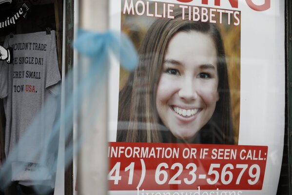 FILE - In this Aug. 21, 2018, file photo, a poster for then-missing University of Iowa student Mollie Tibbetts hangs in the window of a local business in Brooklyn, Iowa. In a victory for prosecutors, a judge ruled Monday, Dec. 23, 2019, that they can use key evidence against the man charged with killing Tibbetts. Judge Joel Yates agreed with prosecutors that some statements made by the suspect, Cristhian Bahena Rivera, must be suppressed because they came during an interrogation after he was not fully read his legal rights. (AP Photo/Charlie Neibergall, File)
