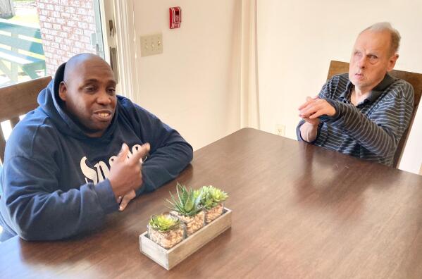Tyrone T., left, and Jack L., discuss their jobs which have been on hold because of the COVID 19 pandemic in this April 1, 2021, photo at the Springfield, Ill., group home they live in operated by Sparc, an agency devoted to assisting people with intellectual and developmental disabilities. A state study prompted by a federal consent decree reports that it would cost the state $329 million this year alone to meet the 2011 court order's demands expanded community-based housing, training and the reduction of a list of 18,000 awaiting services. Sparc is prohibited by law from releasing full names of its residents. (AP Photo by John O'Connor)