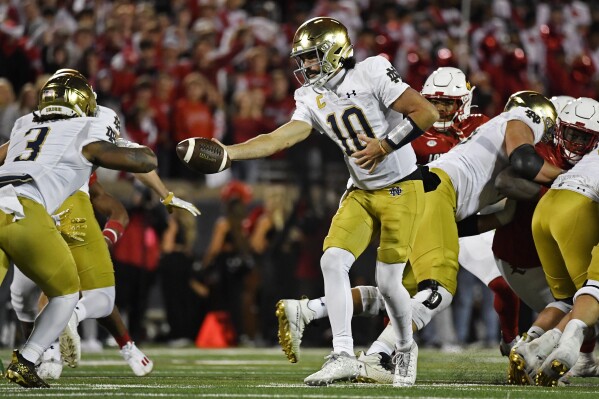 Notre Dame quarterback Sam Hartman (10) hands off the ball to running back Gi'Bran Payne (3) during the second half of an NCAA college football game against Louisville in Louisville, Ky., Saturday, Oct. 7, 2023. (AP Photo/Timothy D. Easley)