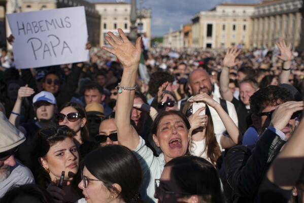 Faithful celebrate after white smoke appeared from the chimney of the Sistine Chapel where 133 cardinals gathered on the second day of the conclave to elect a successor to late Pope Francis, at the Vatican, Thursday, May 8, 2025. (AP Photo/Emilio Morenatti)