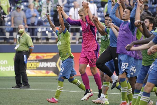 Seattle Sounders players, including forward Raul Ruidiaz, left, and goalkeeper Stefan Cleveland (30) celebrate after an MLS soccer match against the Houston Dynamo, Wednesday, July 7, 2021, in Seattle. Ruidiaz had a goal in stoppage time and the Sounders won 2-0. (AP Photo/Ted S. Warren)