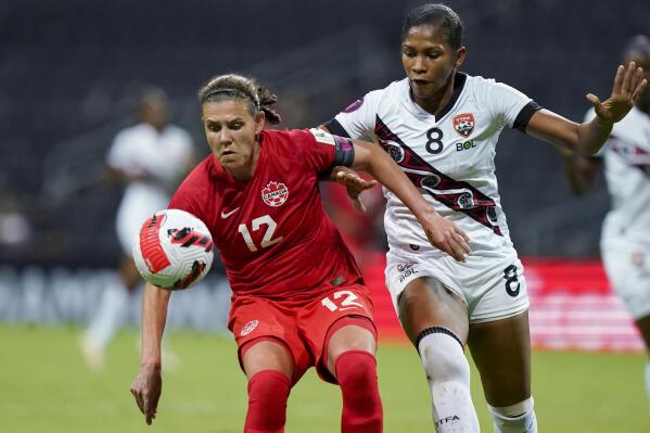 FILE - Canada's Christine Sinclair (12) and Trinidad and Tobago's Victoria Swift compete for the ball during a CONCACAF women's championship soccer match in Monterrey, Mexico, July 5, 2022. Players on the Canadian women's national team says they're outraged by cuts to the women's program and won't participate in team activities. “The time is now, we are taking job action," the team posted to Twitter on Friday, Feb. 10, 2023. The team was scheduled to play in the She Believes Cup starting next week in Orlando, Fla. (AP Photo/Fernando Llano, File)