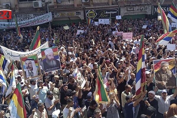 In this photo released by Suwayda24, people stage a protest as they wave the Druze flags in the southern city of Sweida, Syria, Friday, Sept. 8, 2023. The protests in the Druze-majority city have been ongoing for more then two weeks, initially driven by surging inflation and the war-torn country's spiraling economy but later widening to calls for the fall of the Assad government. (Suwayda24 via AP)