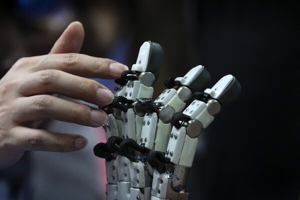 A visitor touches robotic fingers during the annual World Robot Conference at the Etrong International Exhibition and Convention Center on the outskirts of Beijing, Thursday, Aug. 17, 2023. (AP Photo/Andy Wong)