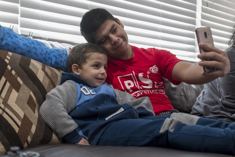 Four-year-old Omar Abu Kuwaik, from Gaza, poses for a selfie with Luis Gomez from Guatemala at the Global Medical Relief Fund residence on Sunday, Feb. 11, 2024, in the Staten Island borough of New York. Omar was the first Palestinian child from Gaza taken in by the Global Medical Relief Fund. The Staten Island charity's founder, Elissa Montanti, has spent a quarter-century getting hundreds of kids free medical care after they lost limbs to wars or disasters, including in Iraq and Afghanistan. (AP Photo/Peter K. Afriyie)
