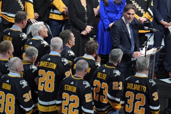 Former Pittsburgh Penguins player Jaromir Jagr, at podium to right, is joined by former teammates as he speaks during a ceremony retiring his uniform number before an NHL hockey game between the Los Angeles Kings and Pittsburgh Penguins in Pittsburgh, Sunday, Feb. 18, 2024. (AP Photo/Gene Puskar)