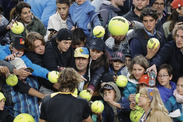 Greece's Stefanos Tsitsipas signs autographs after winning his third round match of the French Open tennis tournament against China's Zhang Zhizhen at the Roland Garros stadium in Paris, Friday, May 31, 2024. (AP Photo/Jean-Francois Badias)