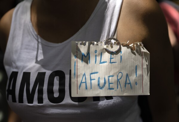 A protester wears the Spanish phrase: "Get out Milei!" in support of a national strike in Argentina against the economic and labor reforms proposed by Argentine President Javier Milei, outside Argentina's embassy in Montevideo, Uruguay, Wednesday, Jan. 24, 2024. (AP Photo/Matilde Campodonico)