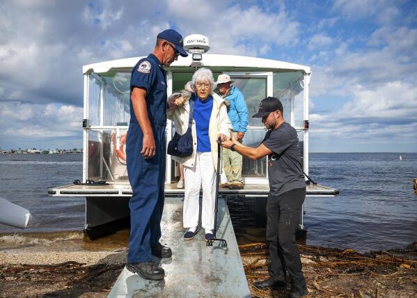 A resident is assisted from a ferry after returning from Pine Island, Fla., after Hurricane Ian, Tuesday, Oct. 4, 2022. (Scott Clause/The Daily Advertiser via AP)