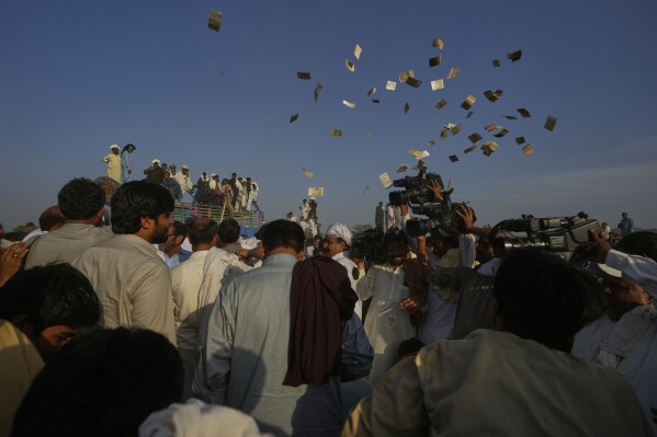 Members of a team blow currency notes in the air as they celebrating after winning a traditional bull race competition, in Malal, a village of Attock district, in Pakistan, Thursday, May 15, 2025. (AP Photo/Anjum Naveed)