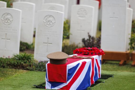 A regimental hat and a poppy wreath are placed on the coffin of an unidentified British World War I soldier during a burial ceremony with full military honors at the Irish Farm Commonwealth War Graves Cemetery in Ypres, Belgium, on Thursday June 30, 2022. Seven World War I soldiers received a ceremonial reburial on Thursday. The remains were discovered near Ypres during a gas pipeline construction. (AP Photo/Olivier Matthys)