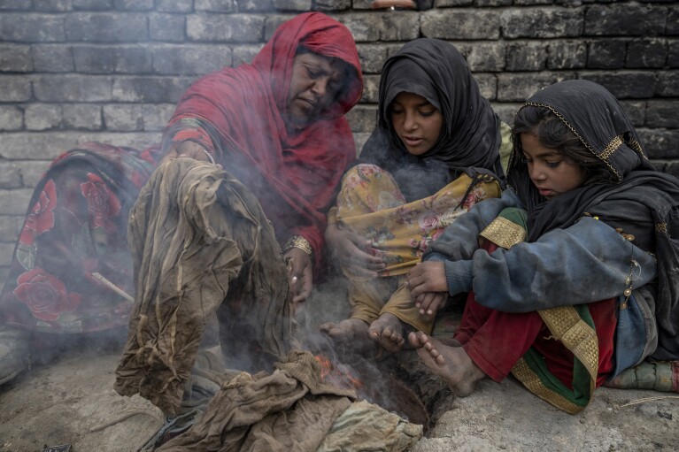 A family who were forced to leave their home, warms up by burning garbage in a camp on the outskirts of Kabul, Afghanistan, Sunday, Jan 22, 2023. (AP Photo/Ebrahim Noroozi)