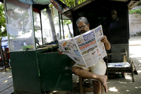 
              FILE- In this Saturday, Nov. 10, 2018, file photo, a Sri Lankan man reads a newspaper reporting about the dissolution of parliament in Colombo, Sri Lanka. Sri Lankan is in the midst of a political crisis set off by the president's decisions to remove the South Asian island nation's prime minister, dissolve Parliament and call snap elections. The moves have triggered public protests and international criticism, including from some of the country's biggest donors. (AP Photo/Eranga Jayawardena)
            