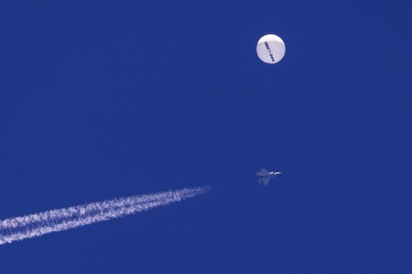 A fighter jet flies near a large balloon drifting above the Atlantic Ocean, just off the coast of South Carolina near Myrtle Beach, Saturday, Feb. 4, 2023. Minutes later, the balloon was struck by a missile from an F-22 fighter jet, ending its weeklong traverse over the U.S. China said the balloon was a weather research vessel blown off course, a claim rejected by U.S. officials. (Chad Fish via AP)