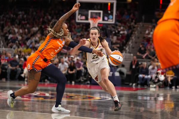Indiana Fever guard Caitlin Clark (22) drives on Connecticut Sun guard Tiffany Mitchell (3) in the second half of a WNBA basketball game in Indianapolis, Monday, May 20, 2024. (AP Photo/Michael Conroy)