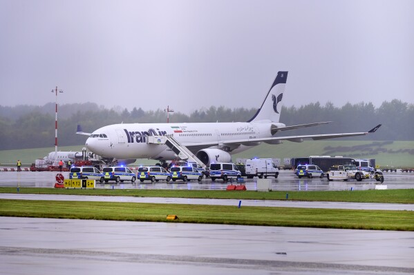Police cars stay in front of an Iran Air aircraft at the Hamburg Airport in Hamburg, Germany, Monday, Oct. 9, 2023. Officials say flights to and from Hamburg Airport were suspended for about 1 1/2 hours after authorities received a threat to a plane that arrived from Iran. (Jonas Walzberg/dpa via AP)