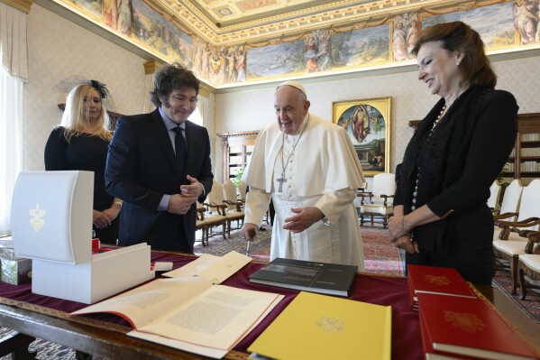 In this image distributed by Vatican Media, Argentine President Javier Milei, second from left, his sister and Secretary-General of the Presidency Karina Milei, left, and Foreign Minister Diana Mondino, right, exchange gifts with Pope Francis as they arrive in the pontiff's studio at The Vatican for a private audience, Monday, Feb. 12, 2024. Milei, who will meet Italian President Sergio Mattarella and Italian Premier Giorgia Meloni later in the day, attended the canonization of the first Argentine female saint, María Antonia de Paz y Figueroa also known as "Mama Antula" in St. Peter's Basilica on Sunday. In the background is Italian Renaissance painter Pietro Cristofaro Vannucci known as Il Perugino's 'The resurrection of Christ' (1499). (Vatican Media via AP, HO)