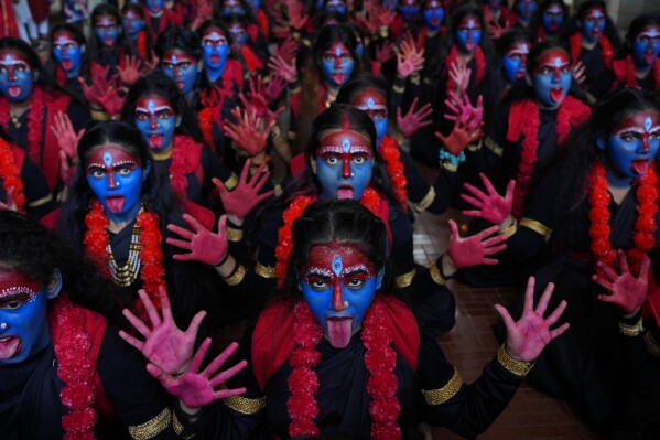 Students at a college with faces painted in blue pose for the media at an event held ahead of Hindu festival Janmashtami in Mumbai, India, Monday, Sept. 4, 2023. The nones in India come from an array of belief backgrounds, including Hindu, Muslim and Sikh. The surge of Hindu nationalism has shrunk the space for the nones over the last decade, activists say. (AP Photo/Rafiq Maqbool)