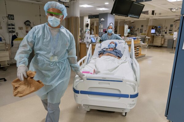 CORRECTS LAST NAME TO VLASSAKOV - In this July 2020, photo released by Brigham and Women's Hospital, members of the transplant anesthesiology team, Drs. Kamen V. Vlassakov front, and Lindsay Wahl lead Carmen Blandin Tarleton to the operating room for her second face transplant at Brigham and Women's Hospital in Boston. Tarleton, who had her first face transplant in 2013, became the first American and only the second person globally to undergo a second face transplant procedure after her first transplant failed. (J. Kiely Jr./Lightchaser Photography/Brigham and Women's Hospital, via AP).