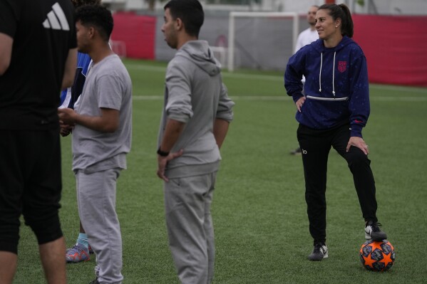 The two-time FIFA Player of the Year Carli Lloyd watches the training of young migrants at Olympiacos Training Center in Athens, Monday, April 22, 2024. Elite American athletes and coaches, including the former US soccer players Carli Lloyd and Cobi Jones, take part in the 2024 spring roster of U.S. Soccer Sports Envoys organized by the U.S. Department of State. (AP Photo/Thanassis Stavrakis)