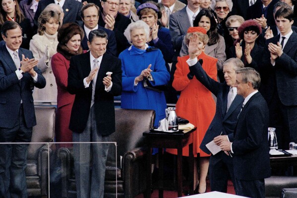 President-elect Ronald Reagan applauds as outgoing President Jimmy Carter waves to the crowd at Reagan's inaugural ceremony, in Washington, Jan. 20, 1981. (AP Photo, File)