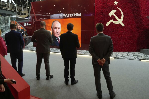 Participants watch a broadcast of Russian President Vladimir Putin's speech on a TV screen during a plenary session of the St. Petersburg International Economic Forum in St. Petersburg, Russia, Friday, June 20, 2025. (AP Photo/Dmitri Lovetsky)