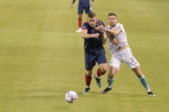 Chicago Fire midfielder Luka Stojanovic (8) and New England Revolution defender Matt Polster (8) battle for control of the ball during the first half of an MLS soccer match in Chicago, Saturday, April 17, 2021. (AP Photo/Mark Black)