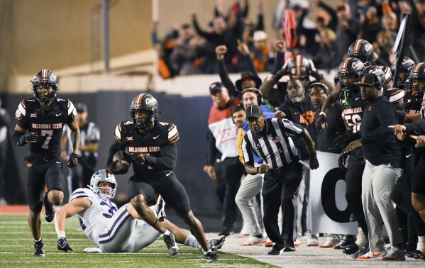 Oklahoma State safety Cameron Epps (7) and Kansas State tight end Ben Sinnott (34) watch as Oklahoma State linebacker Nickolas Martin (4) runs back an interception during the second half of an NCAA college football game Friday, Oct. 6, 2023, in Stillwater, Okla. Oklahoma State won 29-21. (AP Photo/Brody Schmidt)