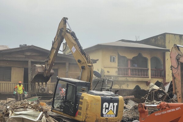 A digger removes debris from the site of a collapsed building in Abuja, Nigeria. Thursday, Aug. 24, 2023. A two-storey building collapsed in Nigeria's capital on Wednesday night, killing two people with many feared trapped amid frantic rescue efforts, emergency officials and residents told The Associated Press. (AP Photo/Chinedu Asadu)