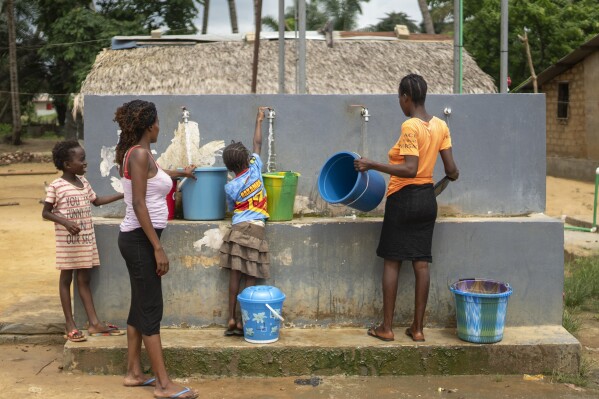 People collect water from a community pump in their village of Tshiende, which is affected by oil drilling, in Moanda, Democratic Republic of the Congo, Saturday, Dec. 23, 2023. (AP Photo/Mosa'ab Elshamy)