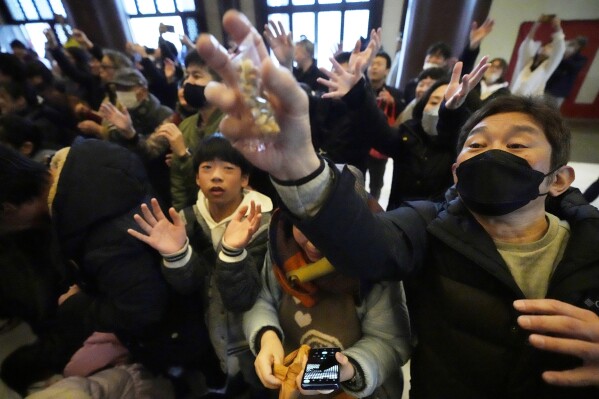 People try to catch lucky beans dispersed by celebrities during the 
