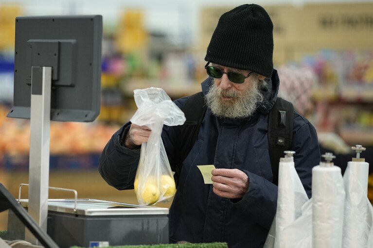 FILE - A man weighs fruit at the "Lenta" hypermarket in Moscow, Russia, Nov. 3, 2023. Russia's economic output fell in 2022 under the impact of Western sanctions, but it's officially forecast to expand by 2.8% this year, a performance that Russian President Vladimir Putin hailed as a sign that the national economy is on the path to recovery. President Vladimir Putin is likely to win another six-year term easily in an election expected in March, using his sweeping grip on Russia’s political scene to extend his tenure of over two decades in power. But he faces daunting challenges. (AP Photo, File)