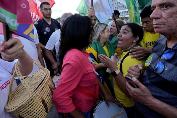 Supporters of Brazil's President Jair Bolsonaro, who is running for reelection, right, confront supporters of Brazil's former President Luiz Inacio Lula da Silva, who is also running for president, during a campaign event at a bus station in Brasilia, Brazil, Tuesday, Oct. 25, 2022. The presidential run-off election is set for Oct. 30. (AP Photo/Eraldo Peres)