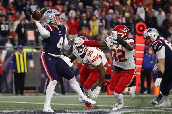 New England Patriots quarterback Bailey Zappe (4) passes under pressure from Kansas City Chiefs defensive tackle Chris Jones (95) and linebacker Nick Bolton (32) during the second half of an NFL football game, Sunday, Dec. 17, 2023, in Foxborough, Mass. (AP Photo/Michael Dwyer)