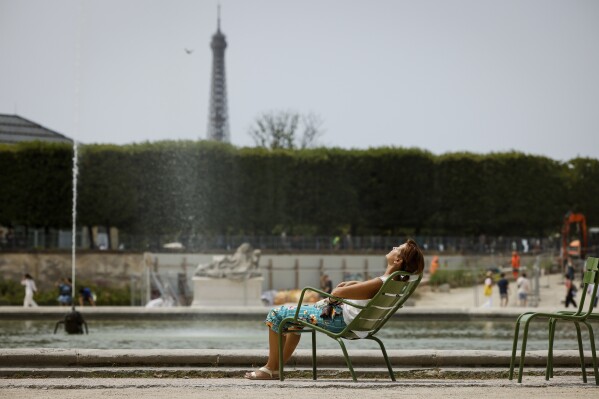 A woman enjoys the sun in the Tuileries gardens, Monday, July 10, 2023, in Paris where temperatures are expected to rise. (AP Photo/Thomas Padilla)