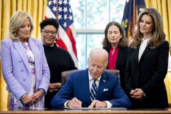 President Joe Biden, accompanied by from left, first lady Jill Biden, Office of Management and Budget director Shalanda Young, White House Gender Policy Council director Jen Klein, and Women's Alzheimer's Movement founder Maria Shriver, signs a presidential memorandum that will establish the first-ever White House Initiative on Women's Health Research in the Oval Office of the White House, Monday, Nov. 13, 2023, in Washington. (AP Photo/Andrew Harnik)