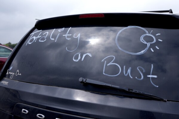 A vehicle with Oklahoma license plates has writing on the rear window that reads, "Totality or Bust", at a total solar eclipse watching event in Paris, Texas, Monday, April 8, 2024. (AP Photo/Tony Gutierrez)