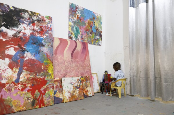 Ace Liam Nana Sam Ankrah, die in juli 2 jaar oud wordt, schildert te midden van zijn kunstwerken in de kunstgalerie van zijn moeder in Accra, Ghana, maandag 27 mei 2024. Ankrah heeft het record als jongste mannelijke kunstenaar ter wereld.  Zijn moeder, Chantelle Cocoa-Egan, zegt dat het allemaal bij toeval begon toen haar zoon, die toen zes maanden oud was, haar verf ontdekte.  (AP Foto/Misper Apawu)