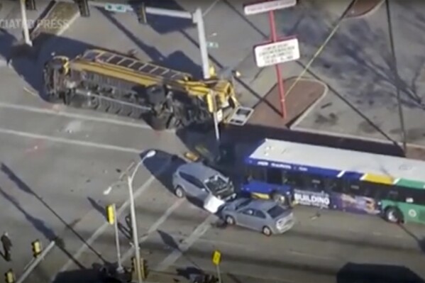This image made from video provided by WISN-TV shows where a vehicle wanted in connection with a homicide in Chicago crashed into a school bus during a police chase in Milwaukee on Wednesday, Nov. 29, 2023, sending multiple people to area hospitals. (WISN-TV via AP)